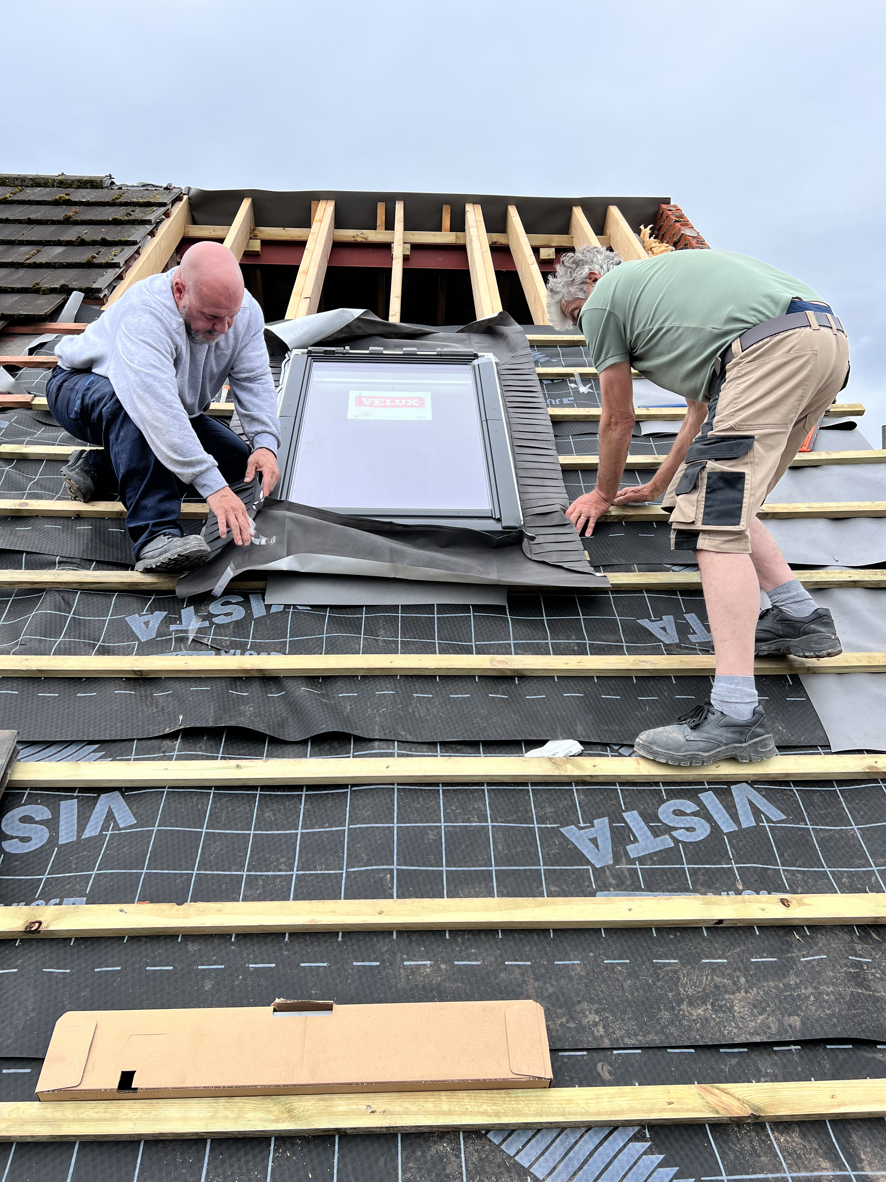 Professional roofers repairing a residential roof with scaffolding